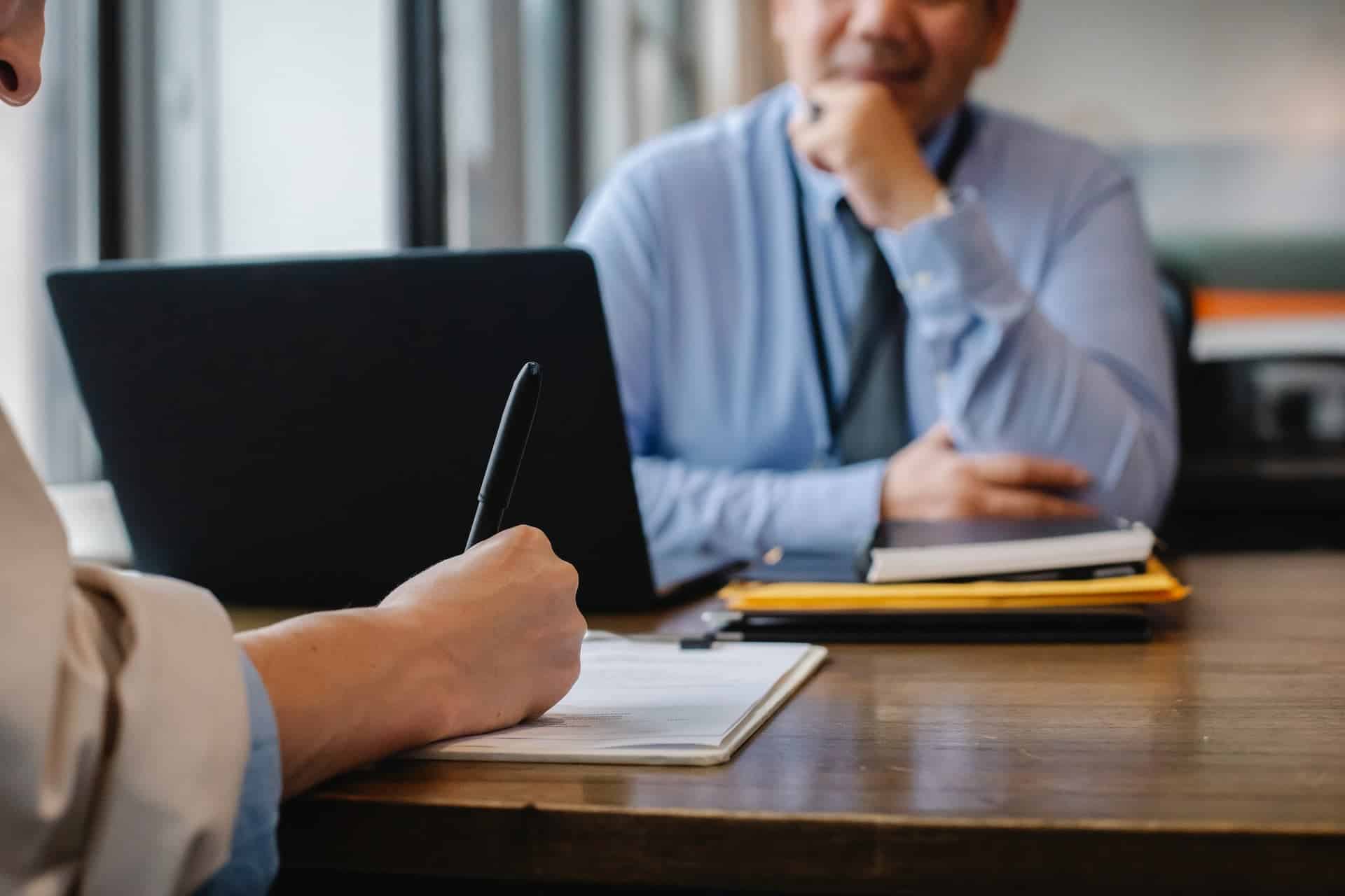 business man at desk with boss who is giving him a performance review