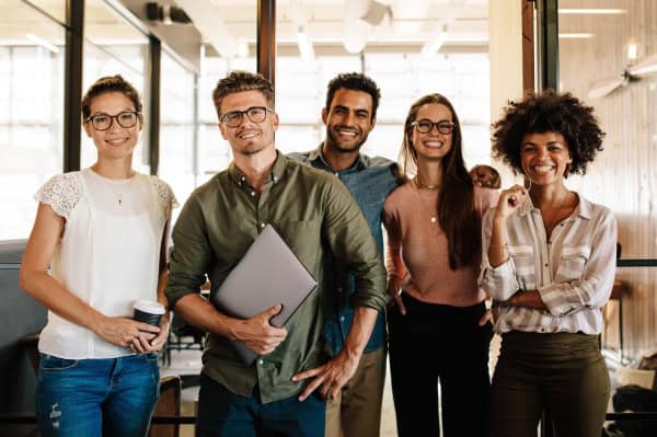 Diverse business people standing together in office and smiling.