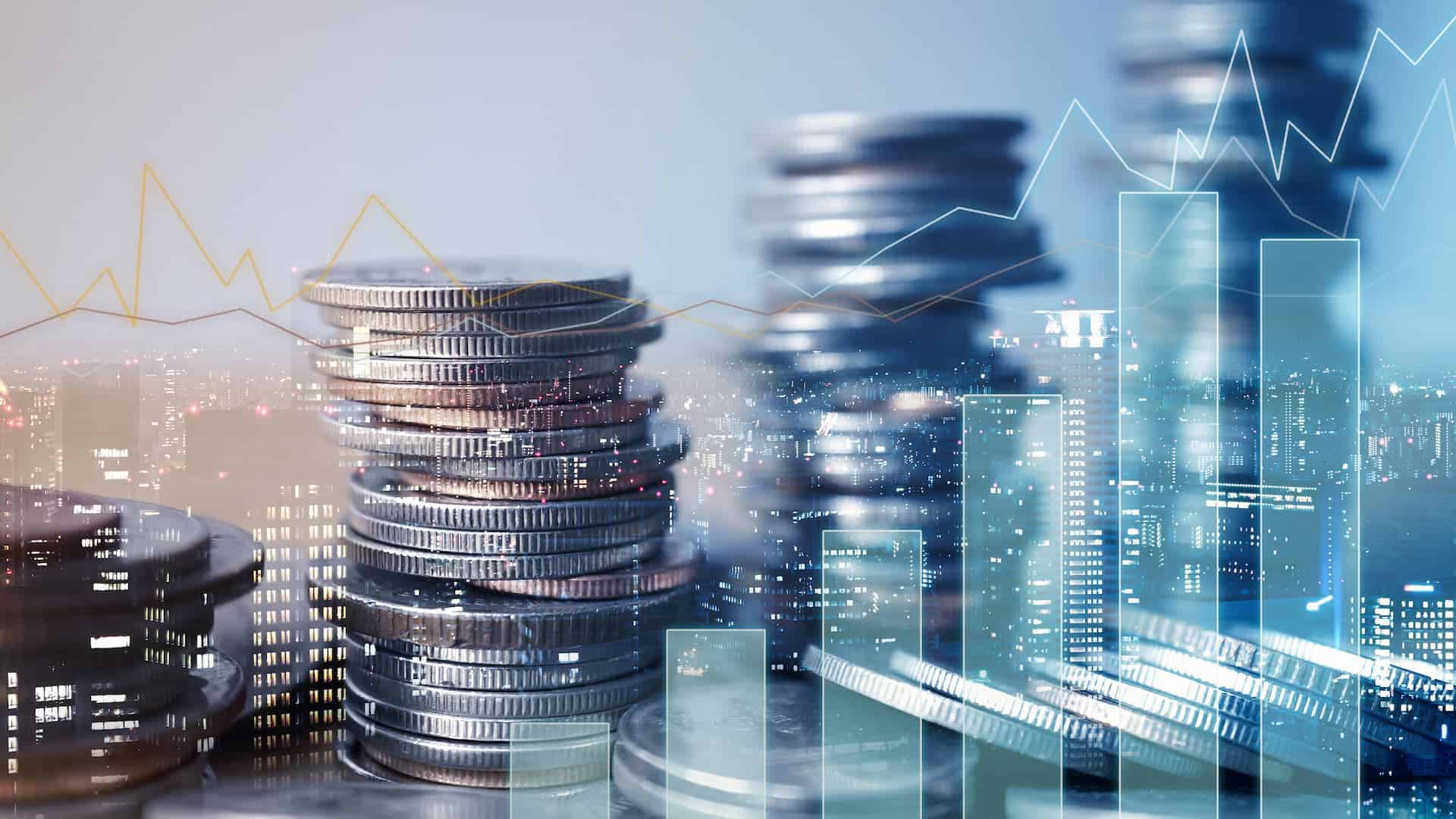 graphs and coins overlayed over a business citycscape.