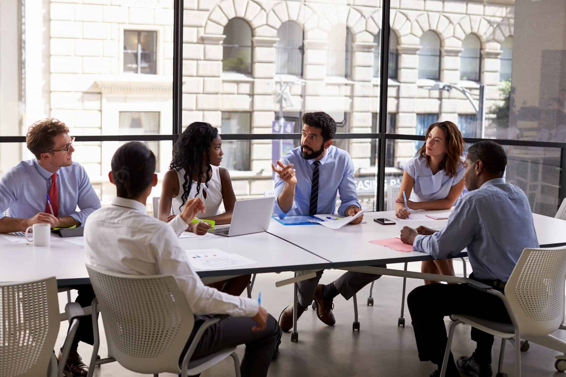 Close-up of a Corporate business team and manager in a well-lit conference room with floor-to-ceiling windows, engaged in a meeting.