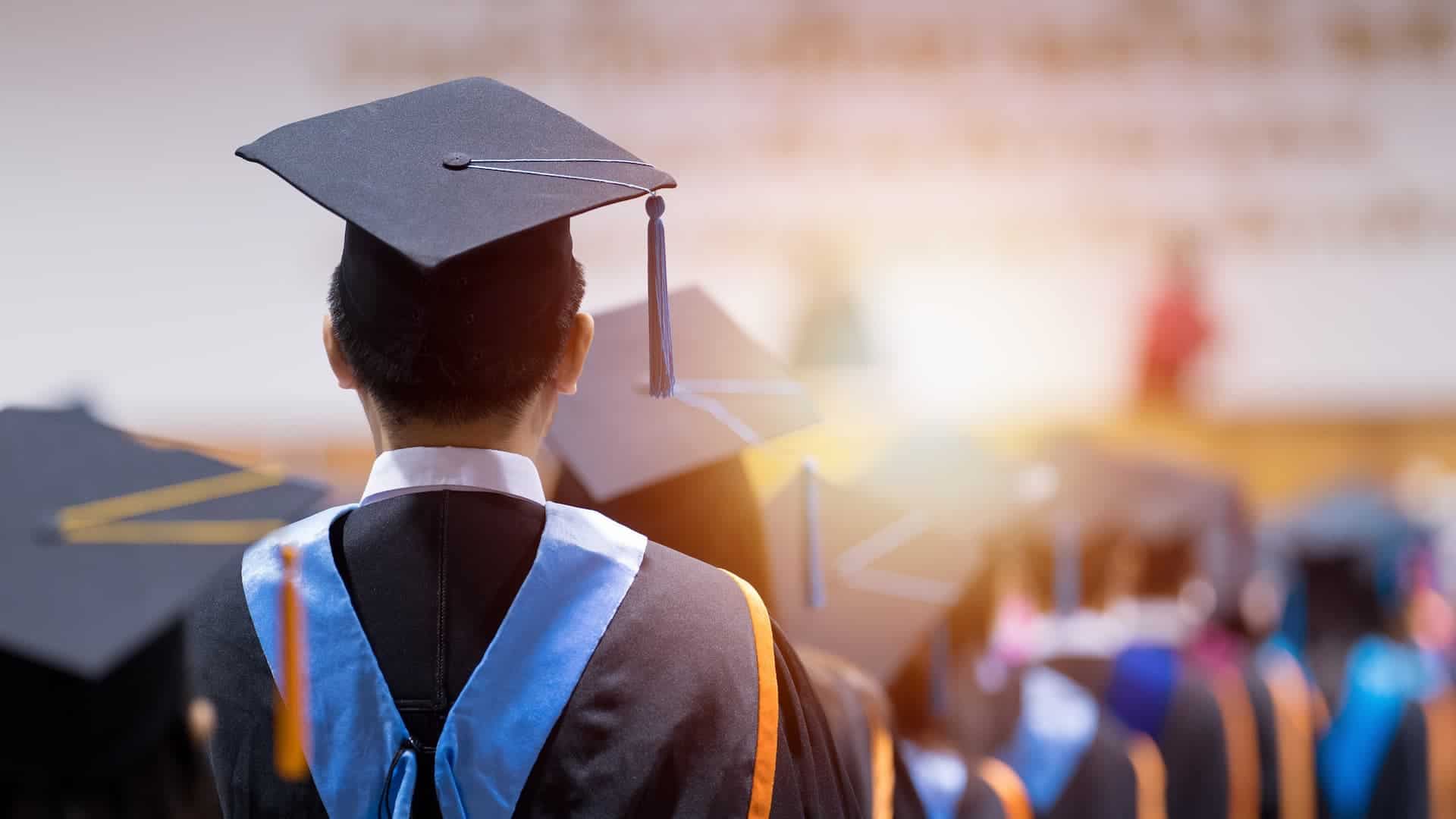 Rear view of university graduates dressed in cap and gown.