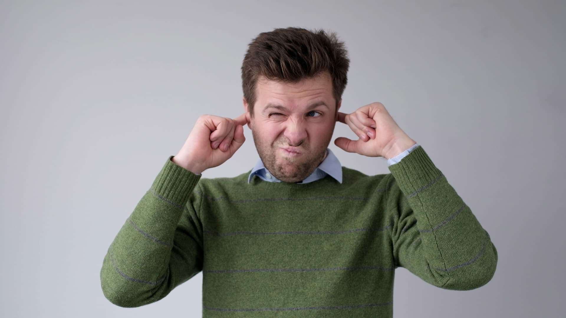 A young man covers his ears to avoid hearing the uncomfortable truth.